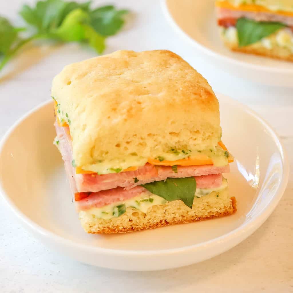close up image of white plate holding one Ham and Chese Biscuit with Herb Mayo