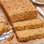 loaf of herb quick bread, with two slices in front and a broken slice on the side