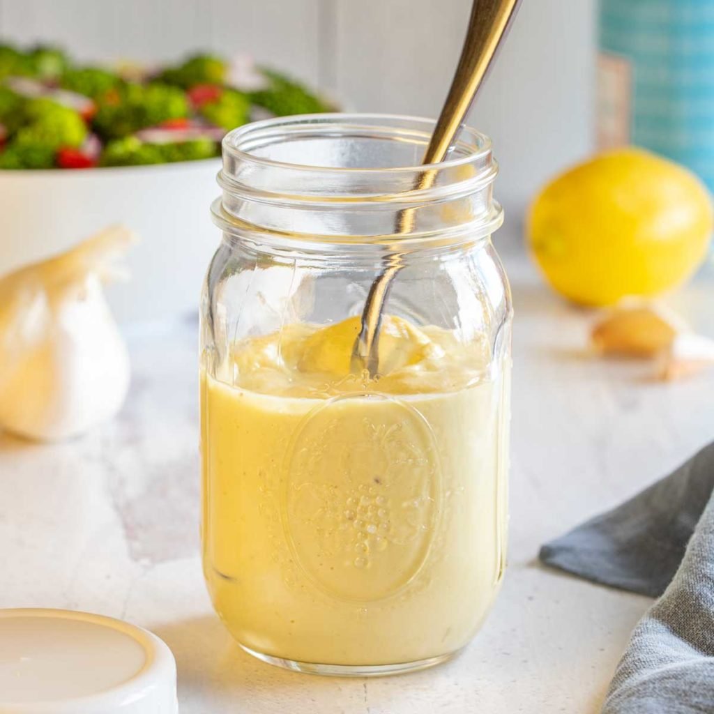 glass mason jar filled with Homemade Caesar Dressing, with a spoon in it