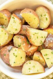 Close-up view of steamed halved new potatoes that have been tossed with melted butter, parsley, and kosher salt.