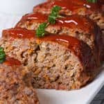 Italian meatloaf on a platter, with a few slices in front to show inside.