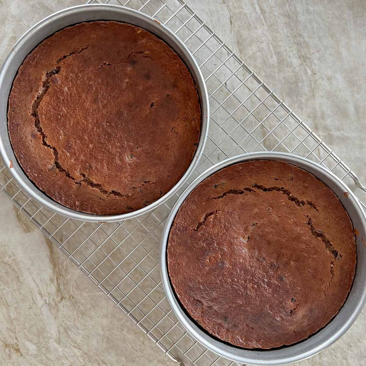 two layers of Blackberry Jam Cake cooling in pans on wire rack
