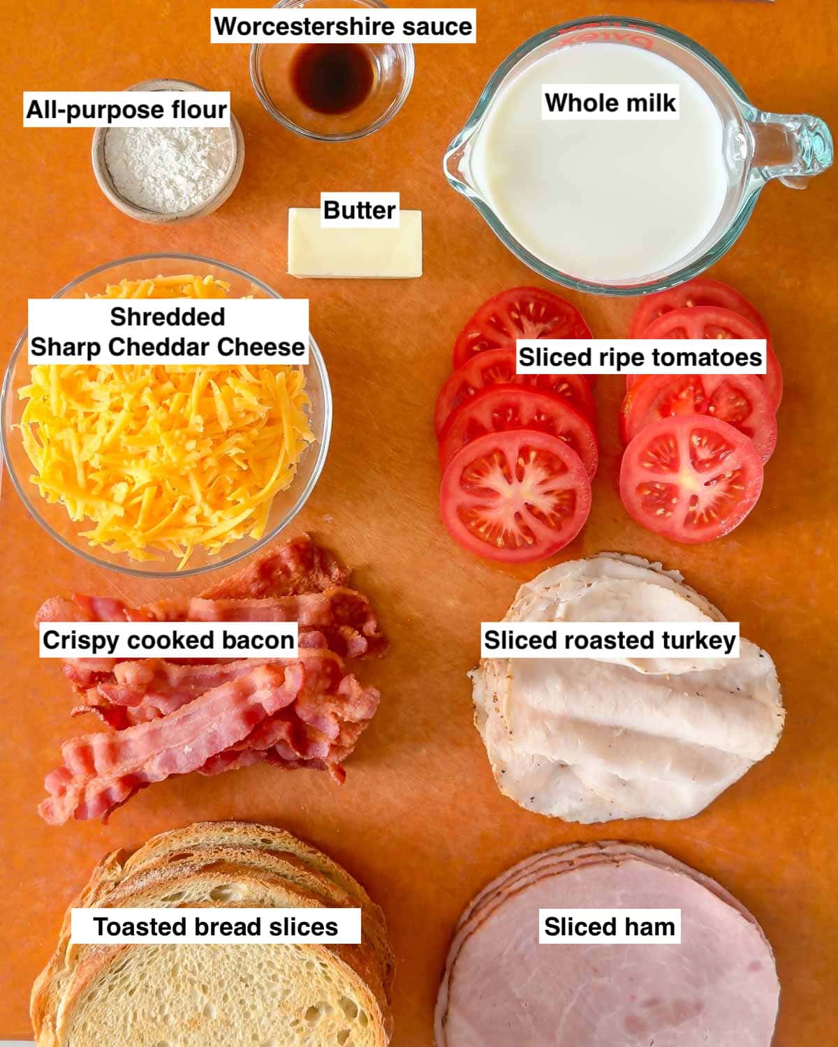 Cutting board holding all 10 ingredients needed to make Hot Brown Sandwiches, labeled.