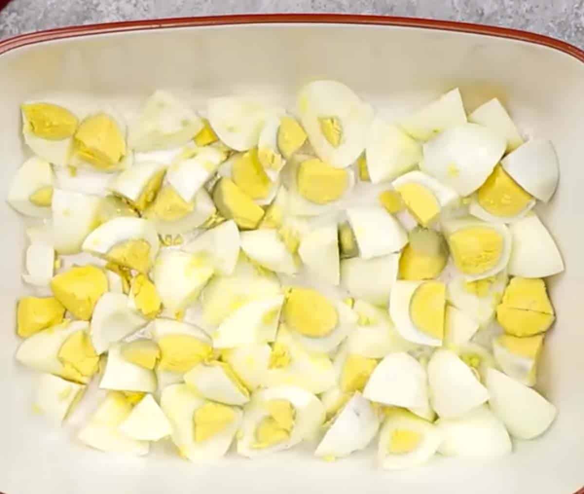 process shot showing chopped hard-boiled eggs in baking dish.
