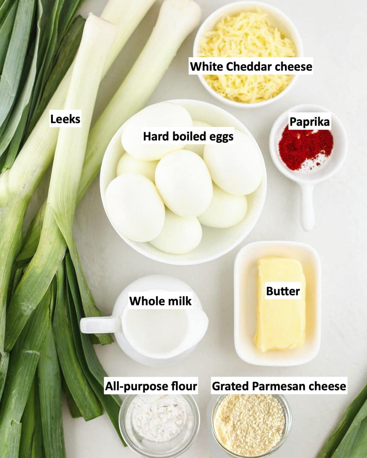 Ingredients to make a leek gratin on a table in bowls with labels.
