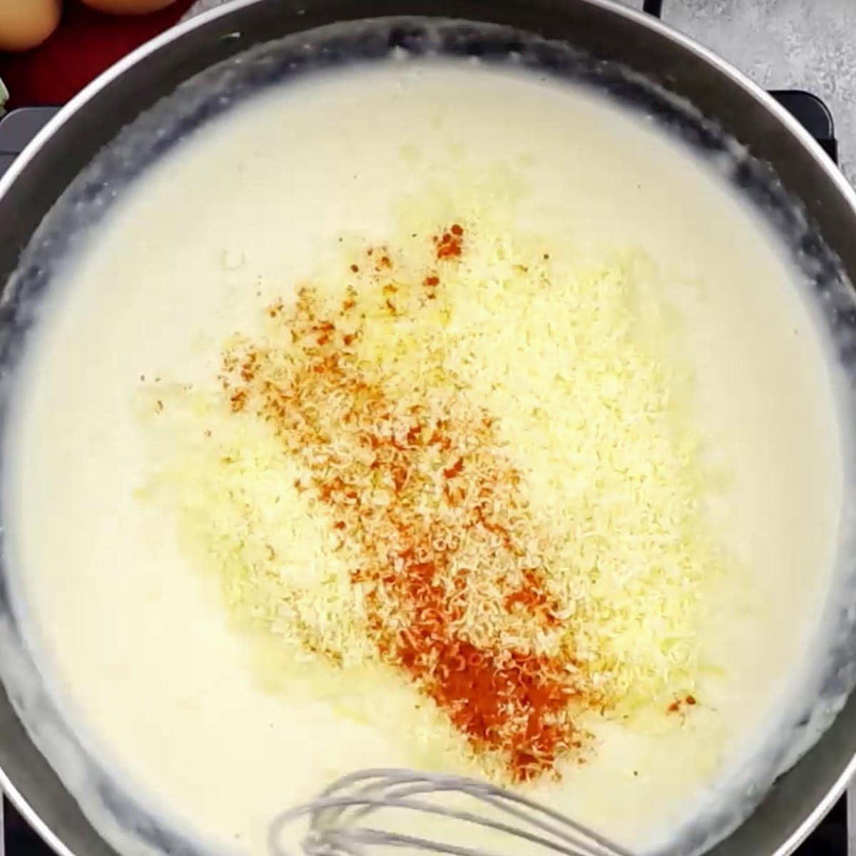 Cheese and seasonings added to the sauce in a skillet.