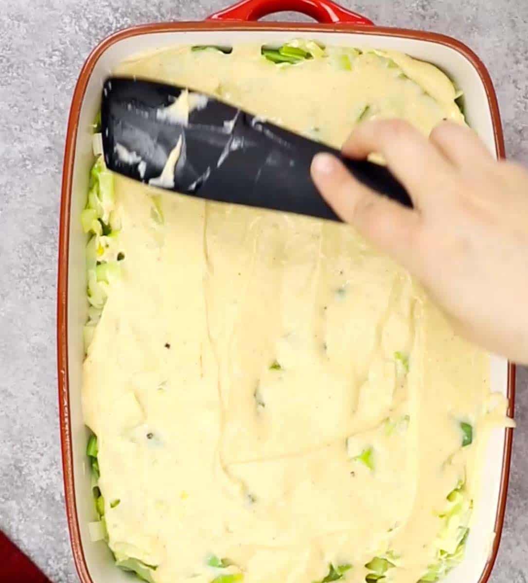 process shot showing spreading sauce over top of leeks