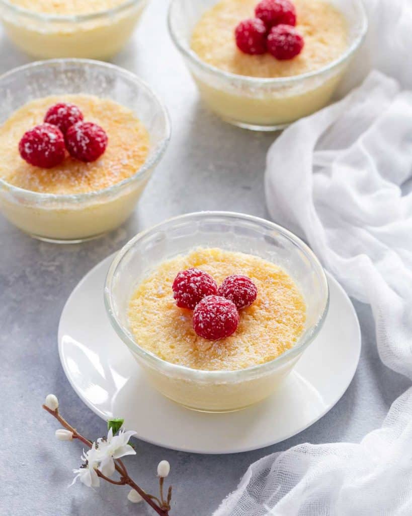 Small glass dishes holding Lemon Pudding Cups, showing alternate garnish of raspberries