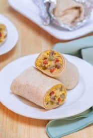white plate holding one Breakfast Burrito, cut in half to show insides