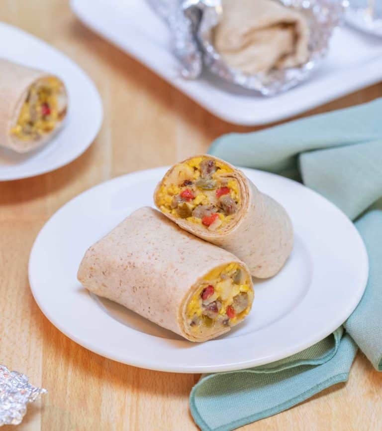 white plate holding one Breakfast Burrito, cut in half to show insides