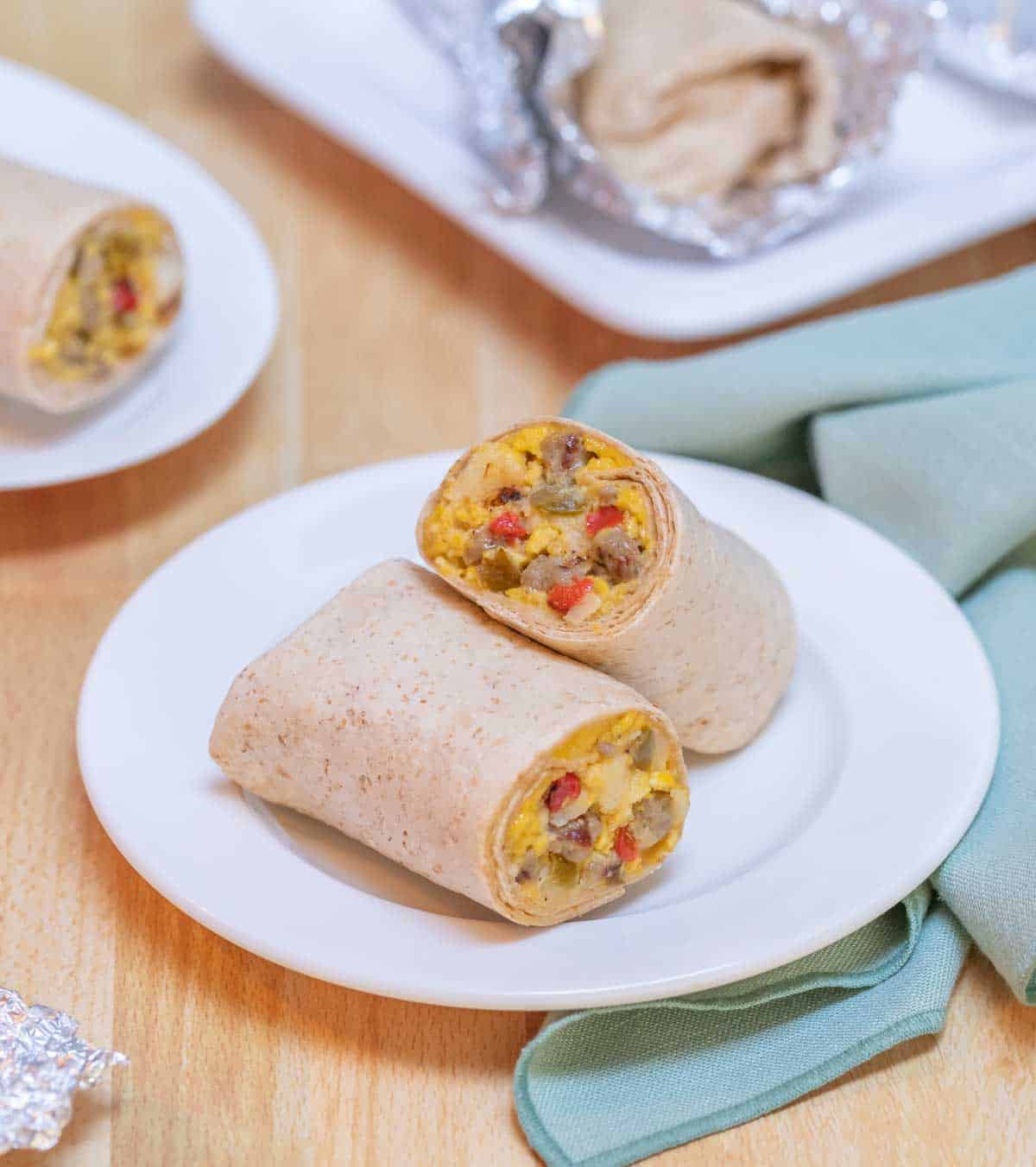 white plate holding one Breakfast Burrito, cut in half to show inside