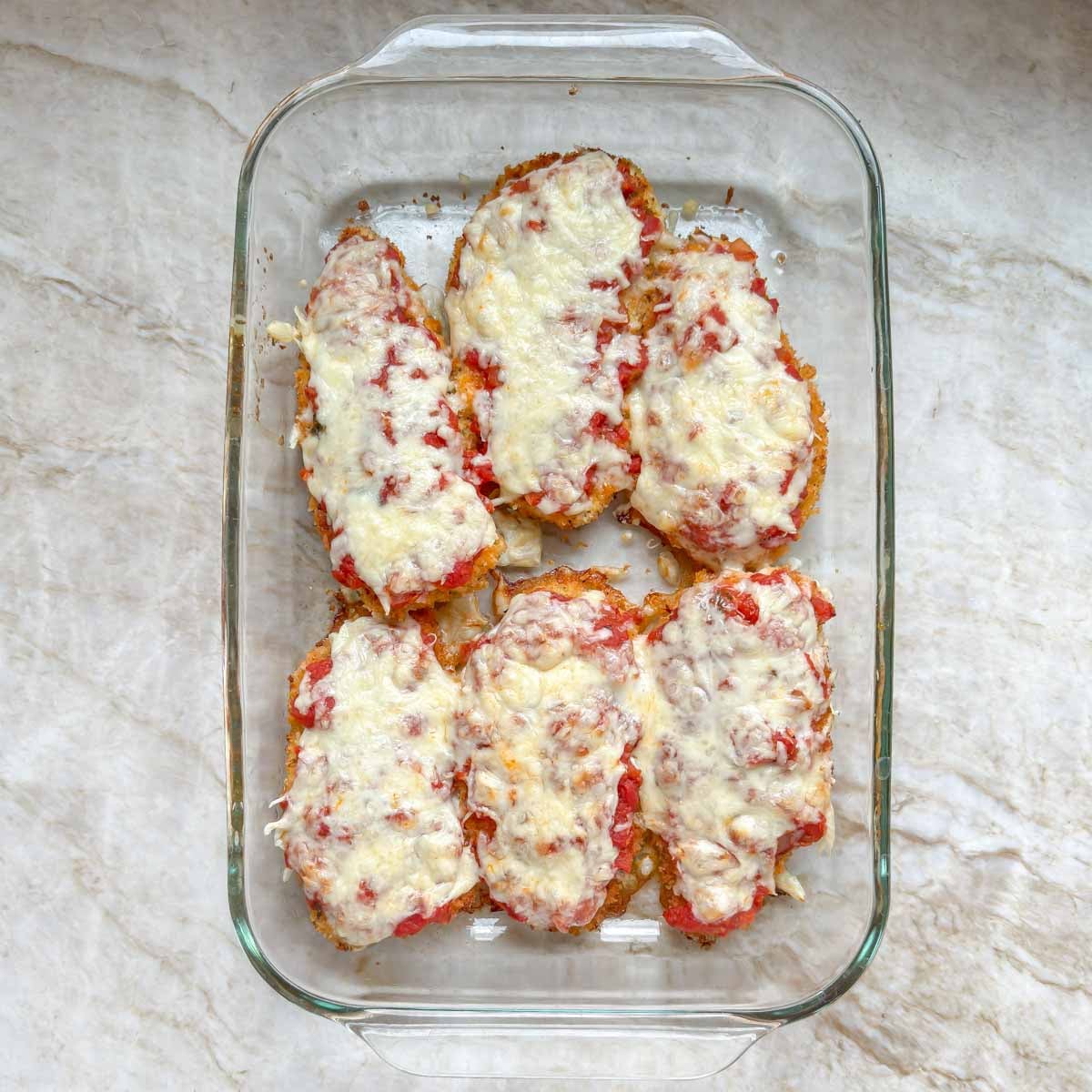Baked chicken parmesan, ready to be plated and garnished.