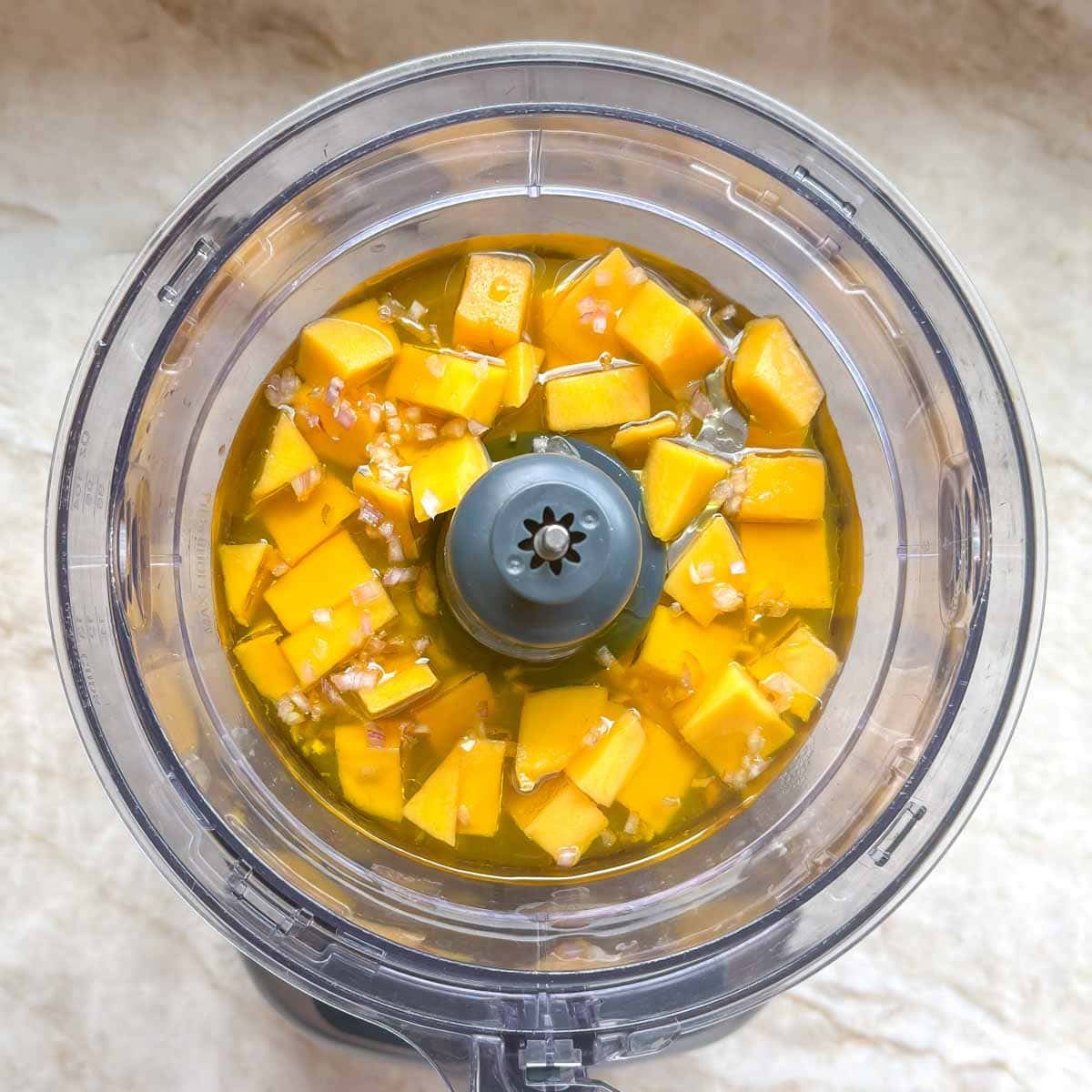 mango vinaigrette ingredients inside a food processor, ready for blending.