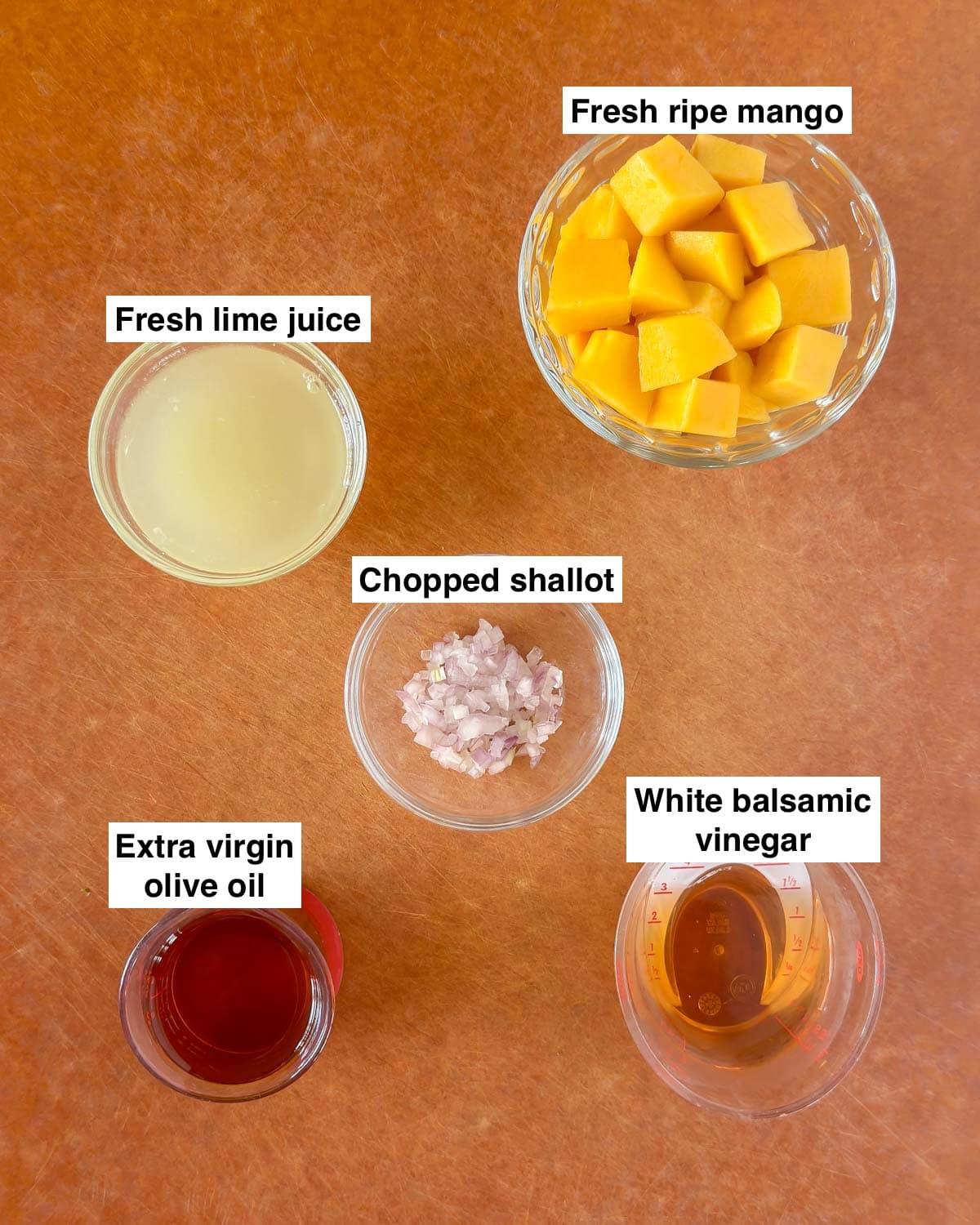 cutting board showing the 5 ingredients needed to make mango vinaigrette, each one prepped.