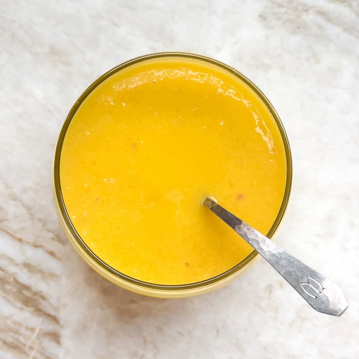 bowl holding finished mango vinaigrette, showing virbrant color and smooth texture.