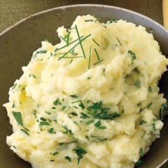 close up showing a bowl of mashed potatoes with parsley and chives