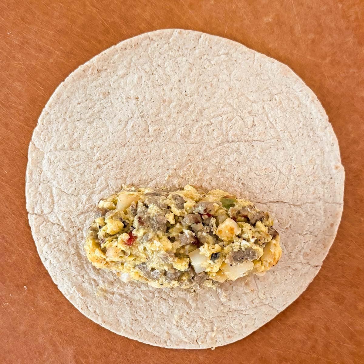 flour tortilla on a cutting board with the filling 1 1/2 inch from the bottom edge and sides.