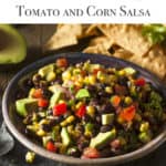 Dark bowl filled with Black Bean, Tomato and Corn Salsa with chips on the side