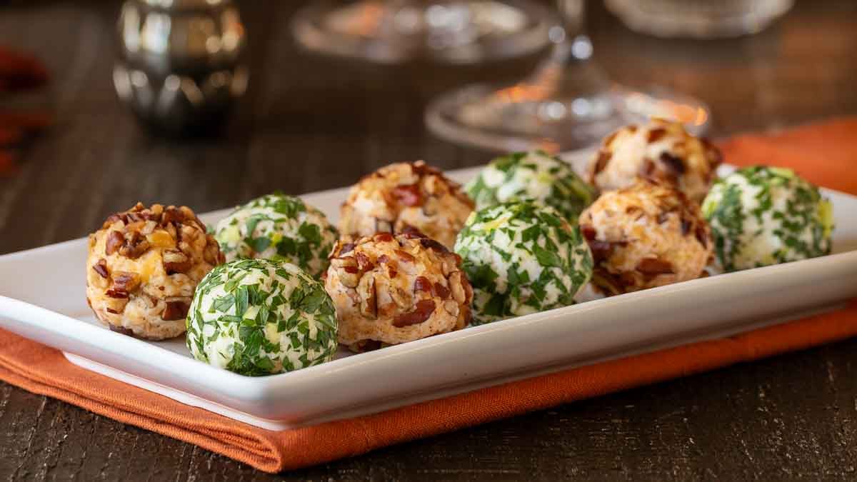 close up view of white platter holding 10 cheese truffles, 5 Cheddar-Pecan and 5 Fontina-Prosciutto cheese balls