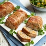 Mini Meatloaves Wrapped In Prosciutto, one sliced, on a white platter