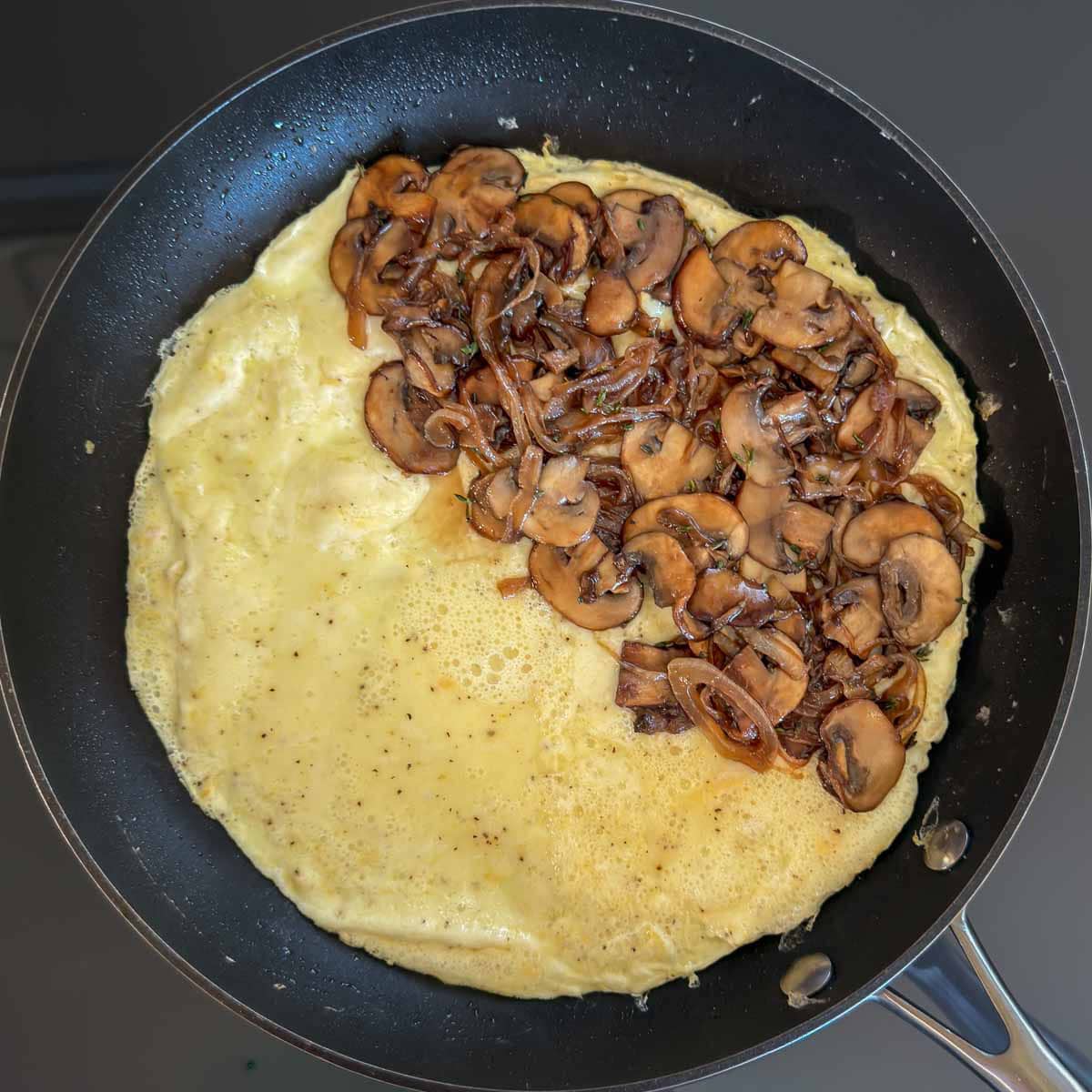 Mushroom filling added to one half of the omelet.