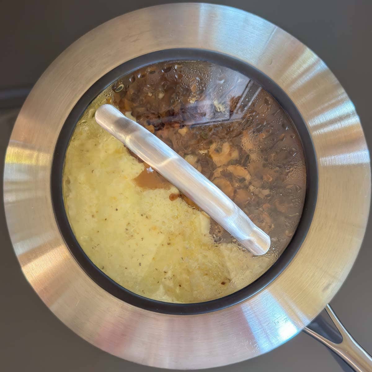 Mushroom omelet covered in skillet to finish cooking.