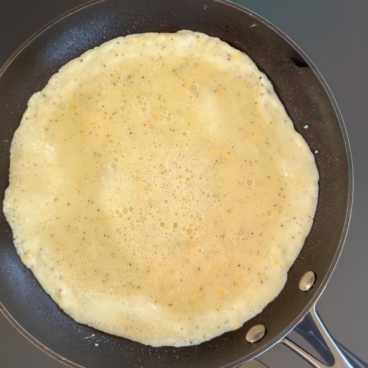 Egg mixture cooking in a nonstick skillet for a mushroom omelet.