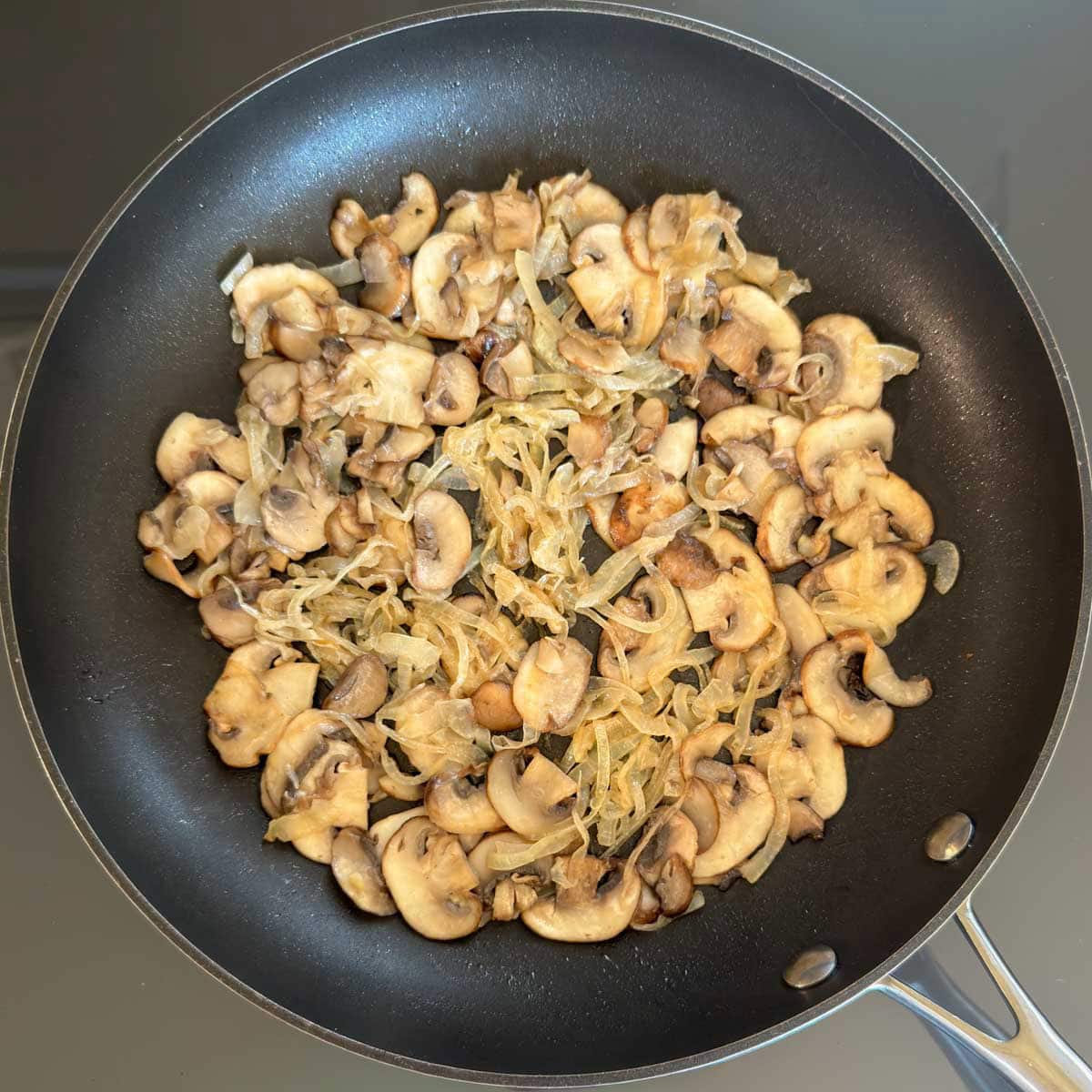 Cremini mushrooms and onions sautéing with thyme in a skillet.