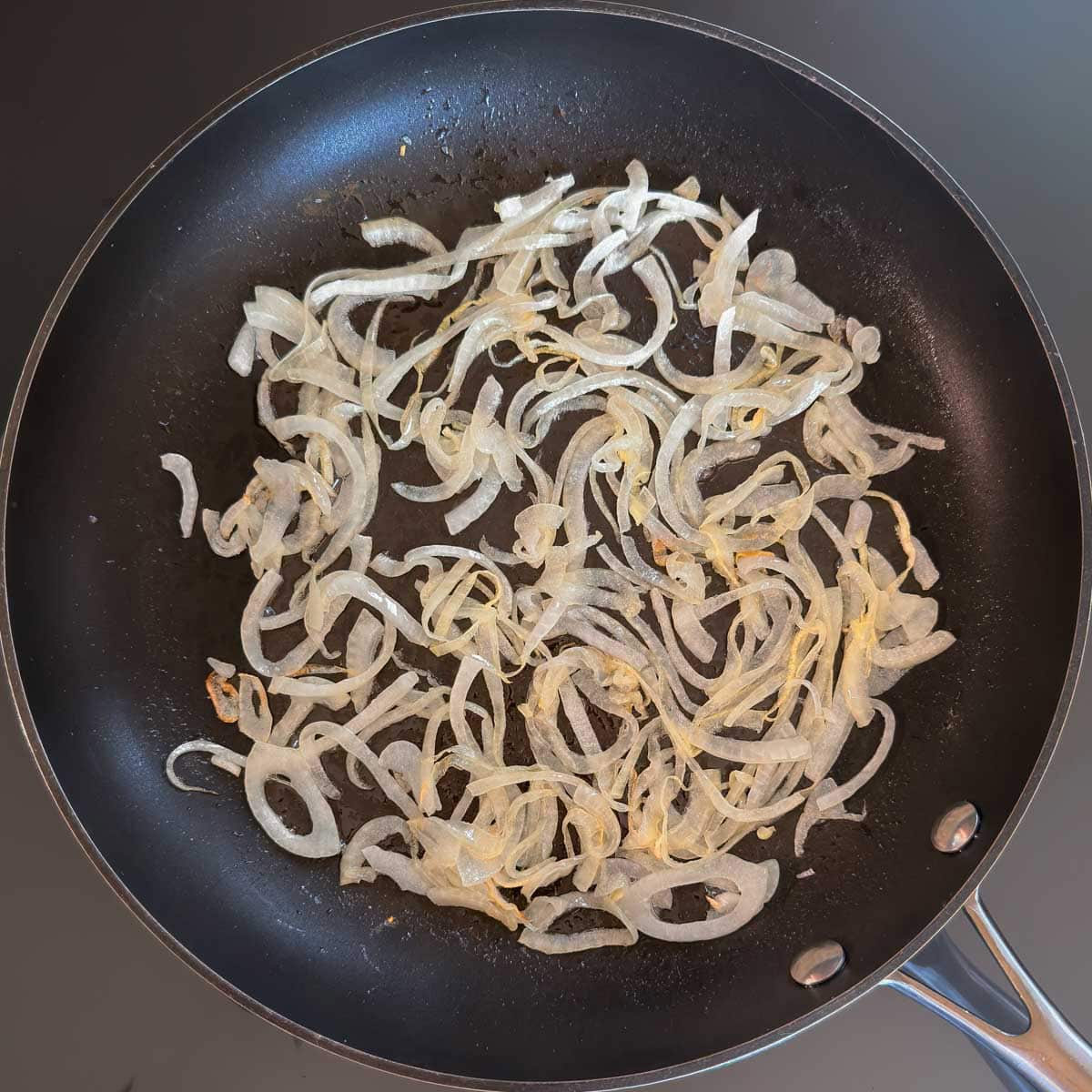 Sliced onions cooking in butter in a nonstick skillet.
