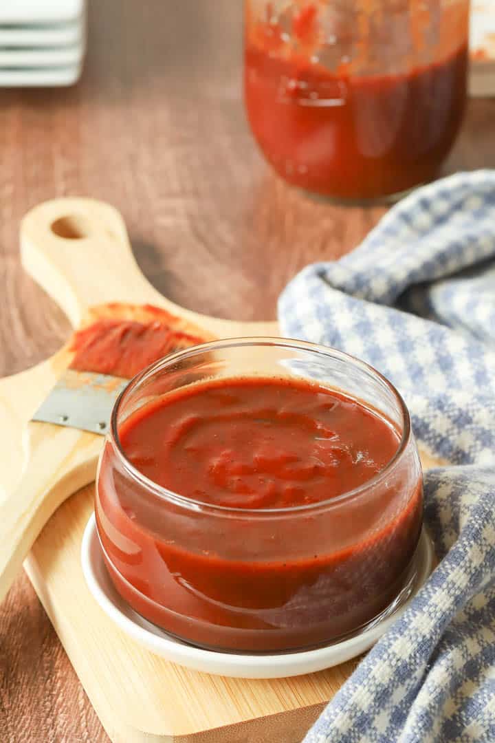 glass bowl holding Oklahoma Barbecue Sauce with a basting brush on the side, with sauce on it.