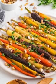 Roasted carrots in oven on a platter garnished with fresh herbs.
