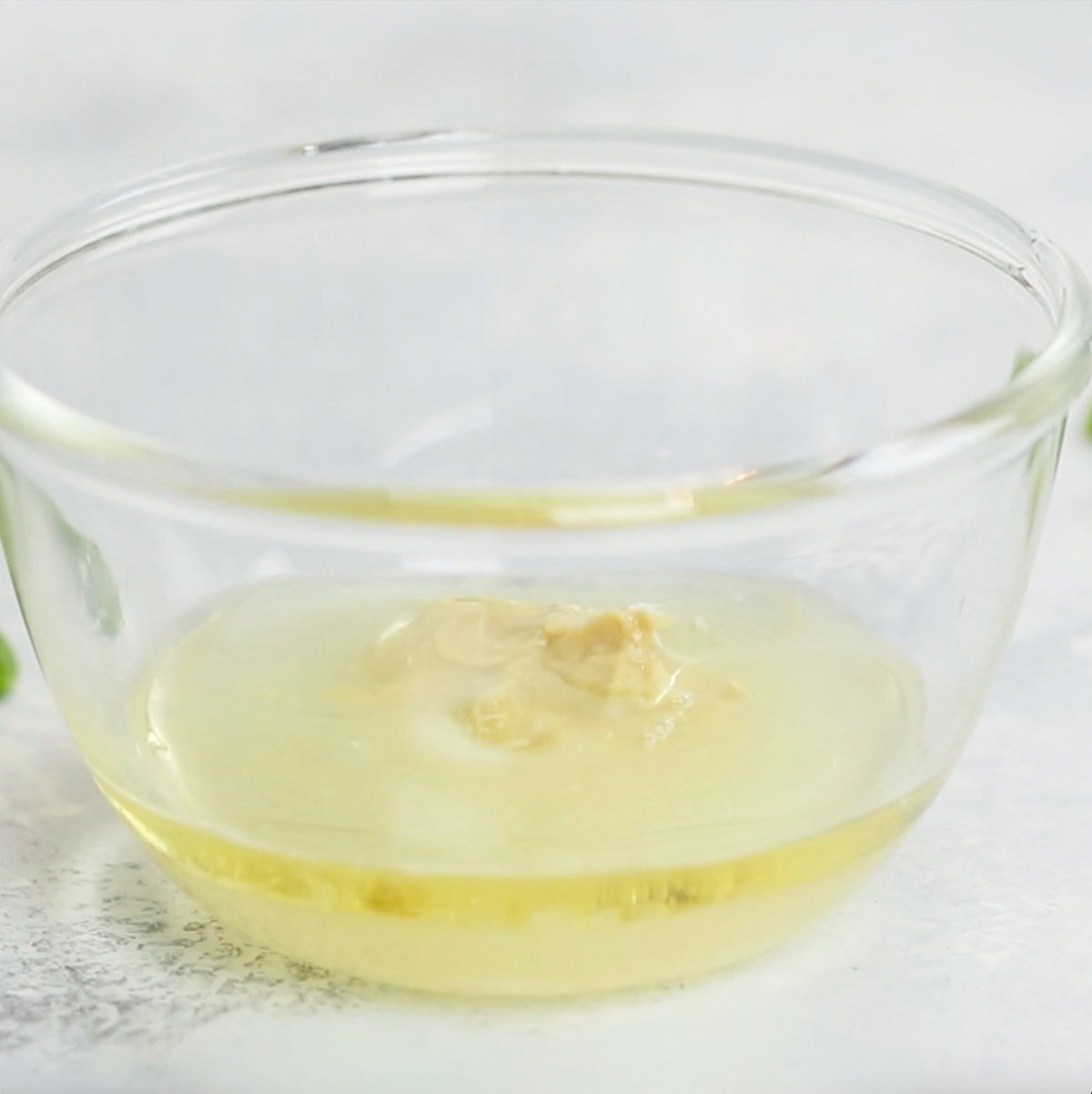 small glass bowl holding ingredients for lemon Dijon Dressing
