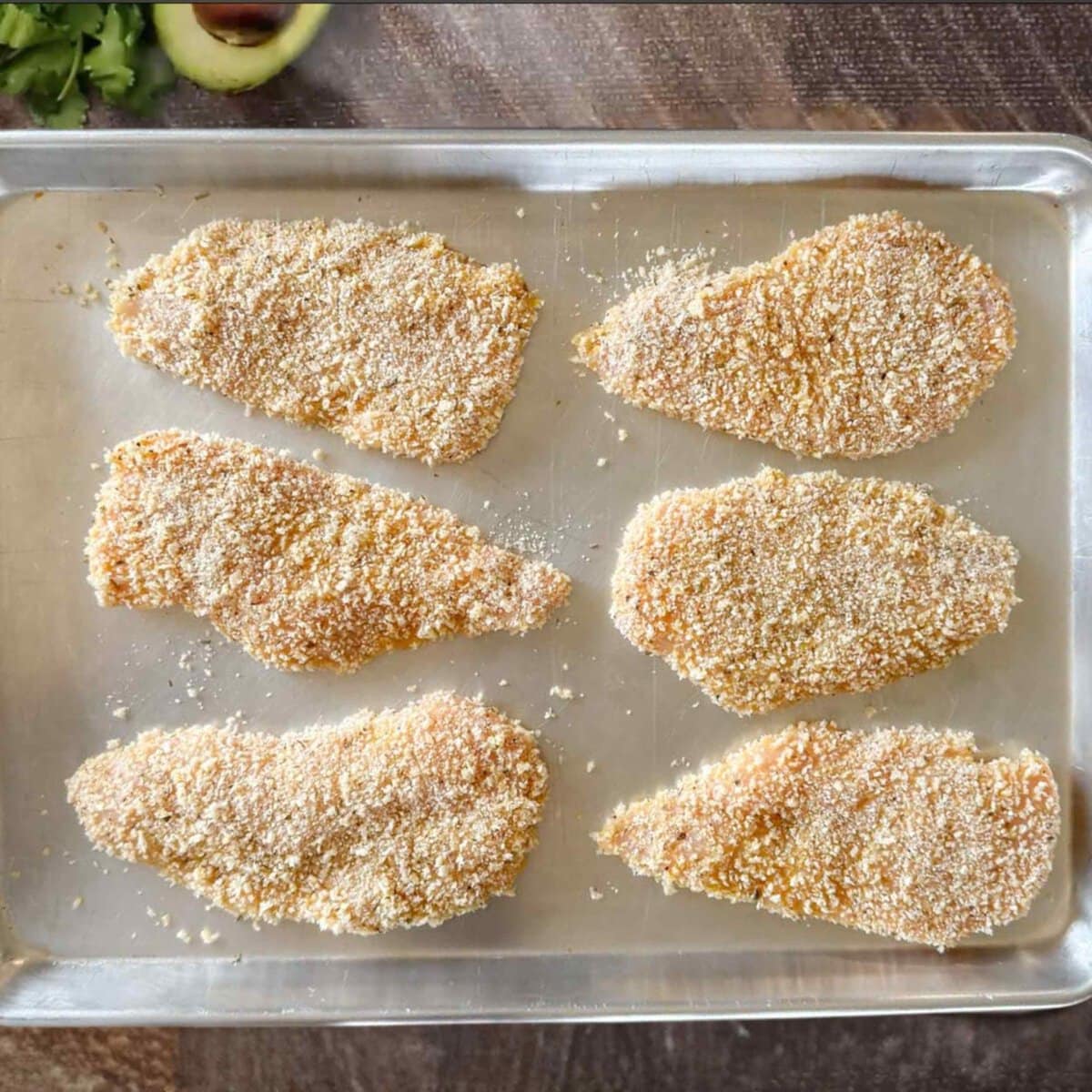 Panko crusted chicken breasts on a baking pan ready to chill. 