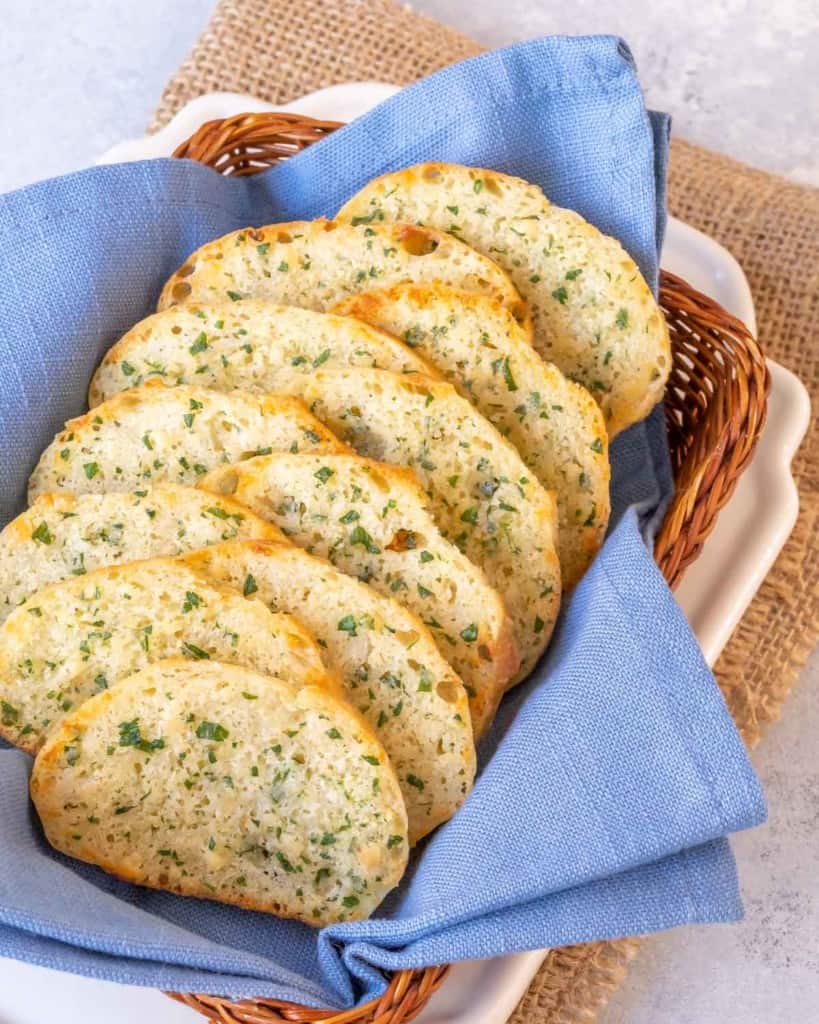 small basket lined with a blue napkin and filled with slices of Parsley Parmesan Crostini Bread