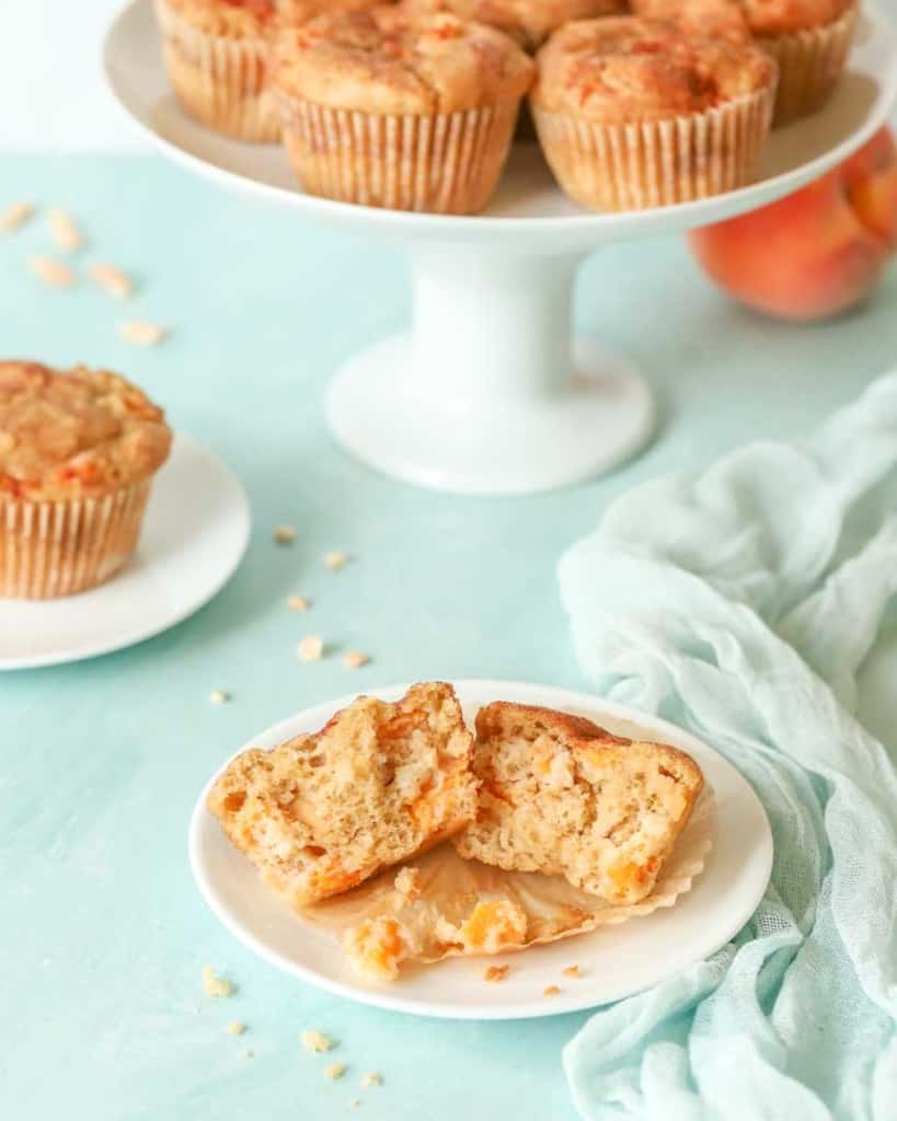 single Peach Muffin split open in front with platter holding more muffins in the background
