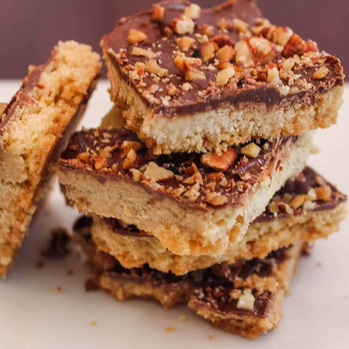 four pecan chocolate toffee bars stacked with one leaning on the side