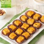 Rectangular white platter holding 15 Pimento Cheese Appetizers with Green Chiles. a cocktail and nuts are partially visible in the background.