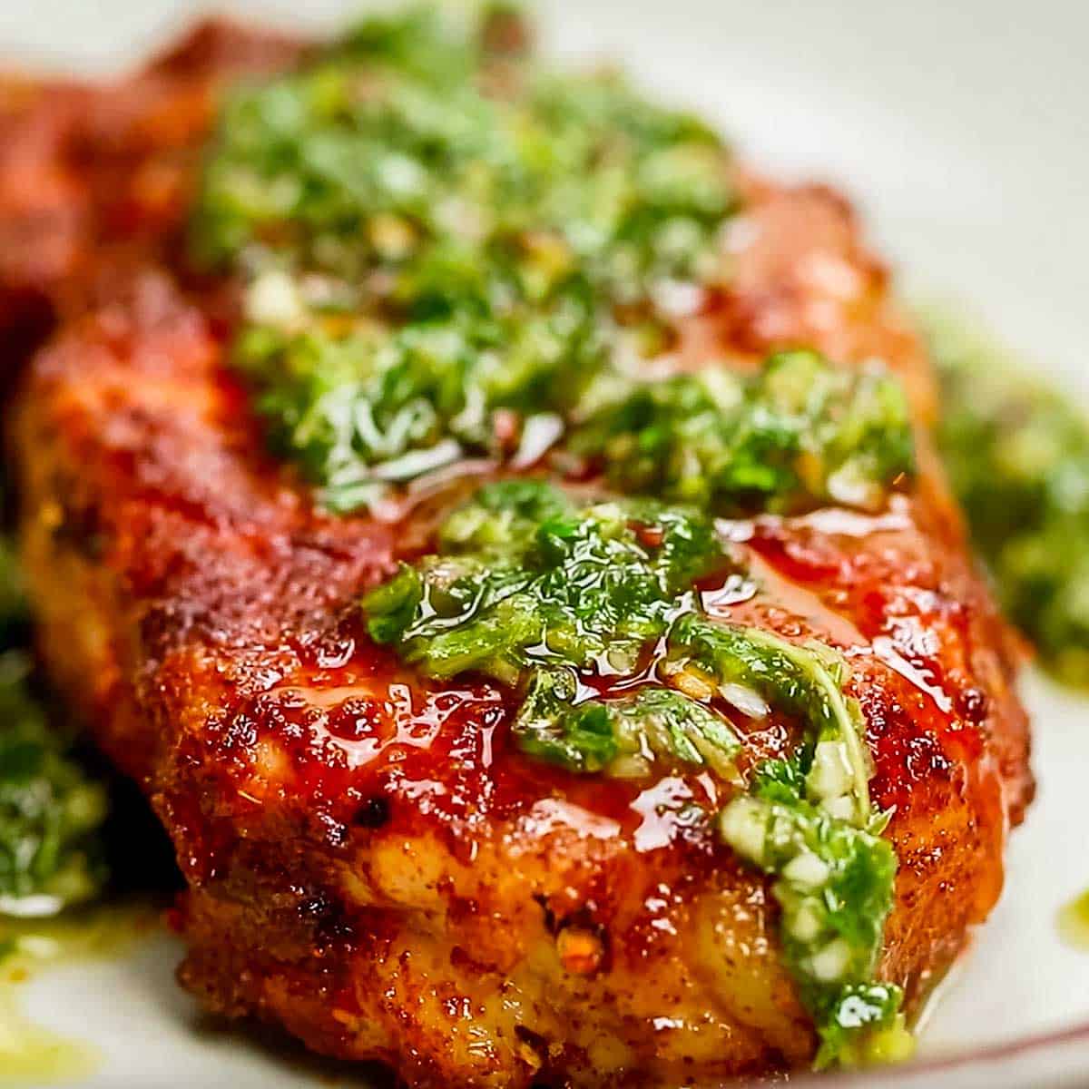 Close up of Grilled Pork Chop topped with Chimichurri Sauce.