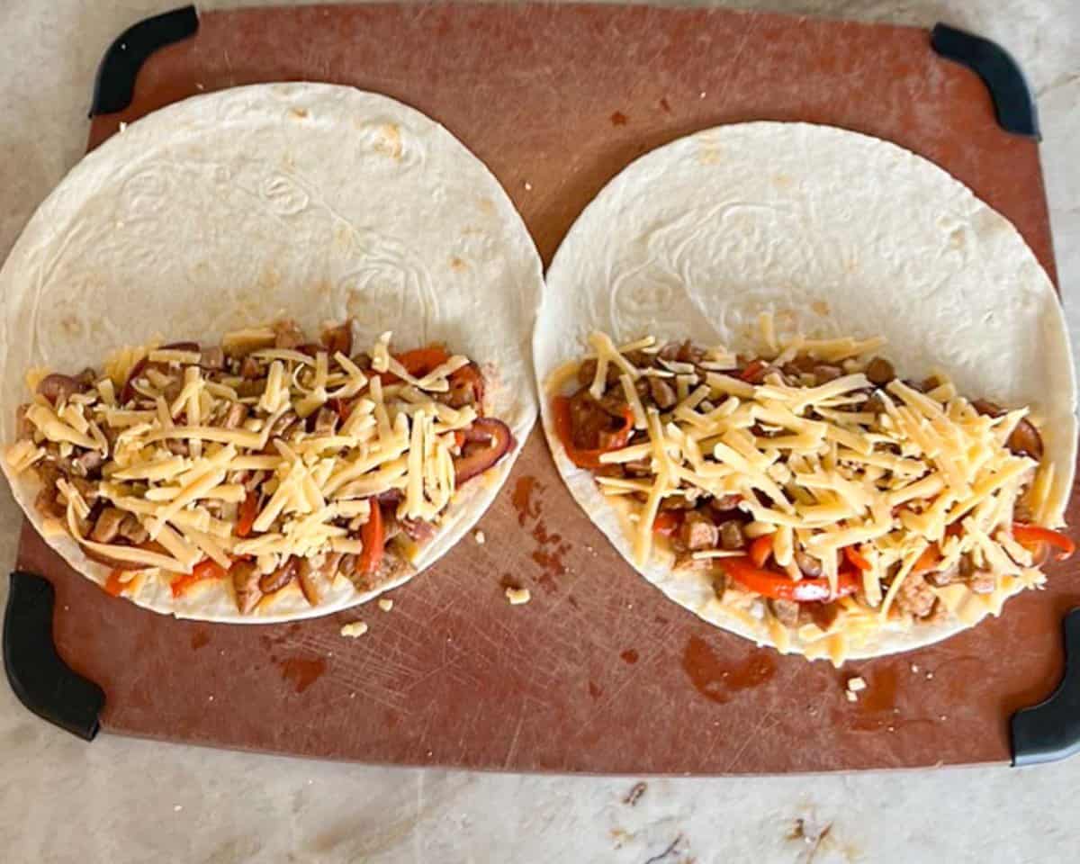two tortillas, open, with pork-onion mixture and grated cheese on half of each.