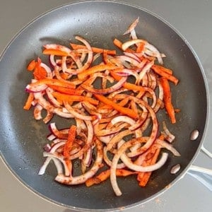 overhead shot of cooking onions and peppers in a skillet