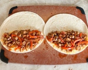two tortillas, open, with pork-onion mixture on half of each