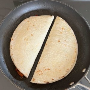 two stuffed tortillas, folded over, cooking in a skillet side by side