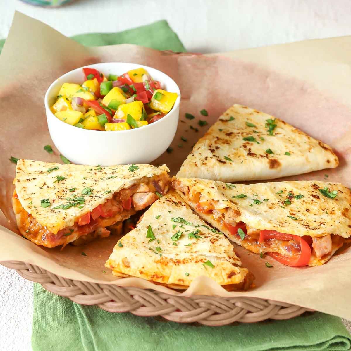Closer view of a wicker plate holding one serving of leftover pork quesadillas.