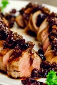close up of sliced cooked pork tenderloin covered with cranberry sauce