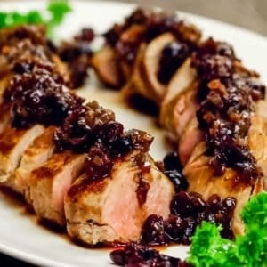 close up of sliced cooked pork tenderloin covered with cranberry sauce