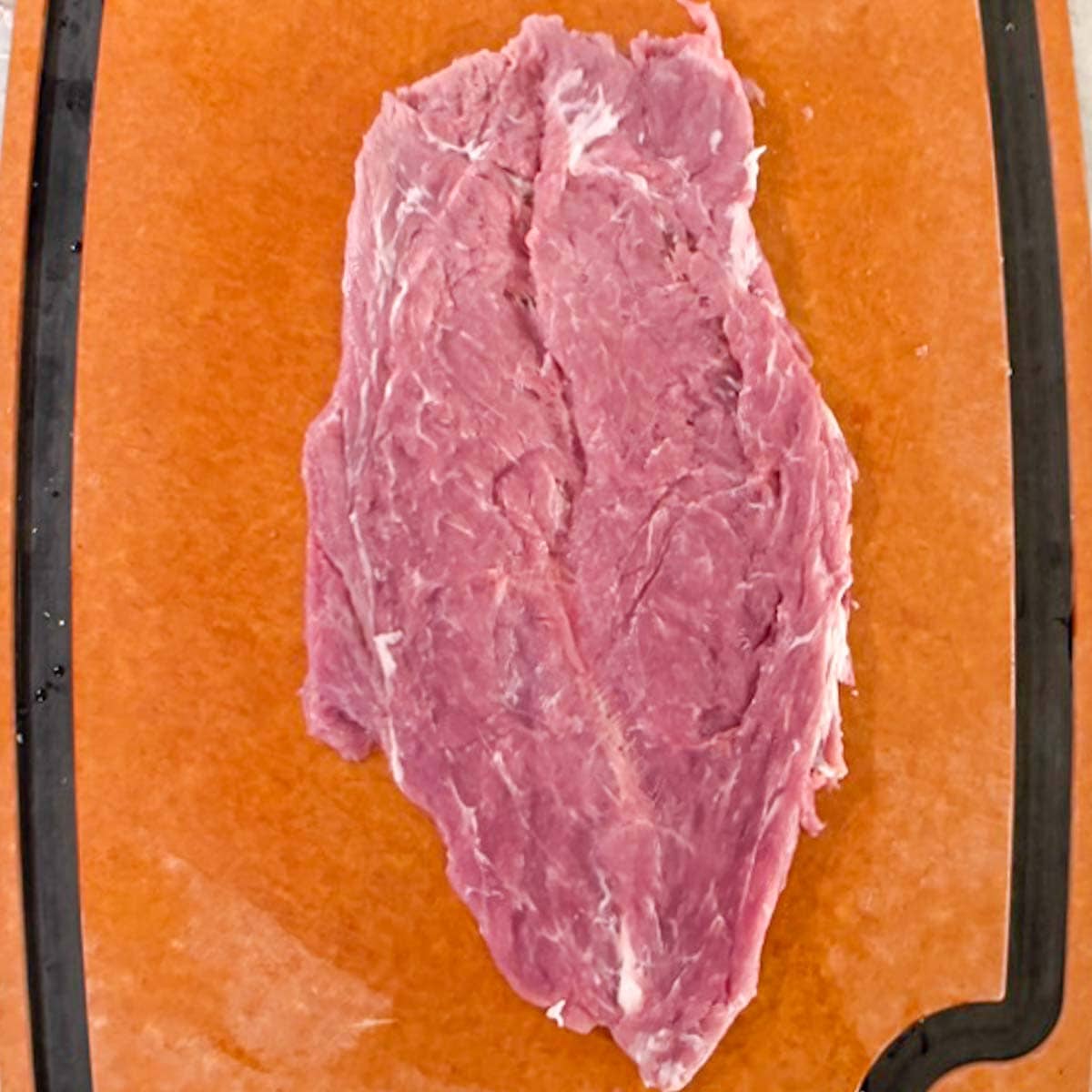 Flattened raw pork tenderloin, the second step in butterflying