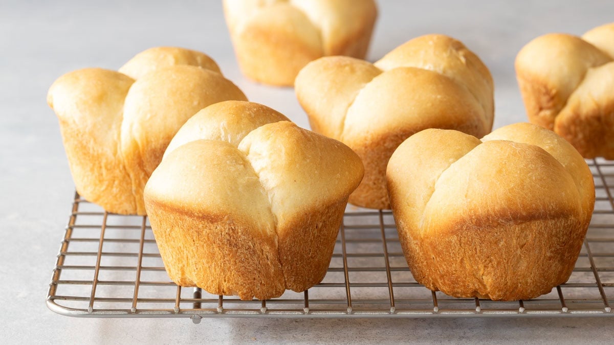 close up of cloverleaf shaped quick dinner rolls sitting on a cooling rack