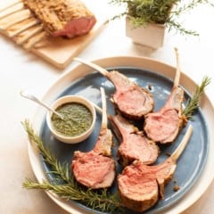 Blue plate with Mustard Crusted Rack of Lamb, sliced, with Fresh Mint Sauce on the side