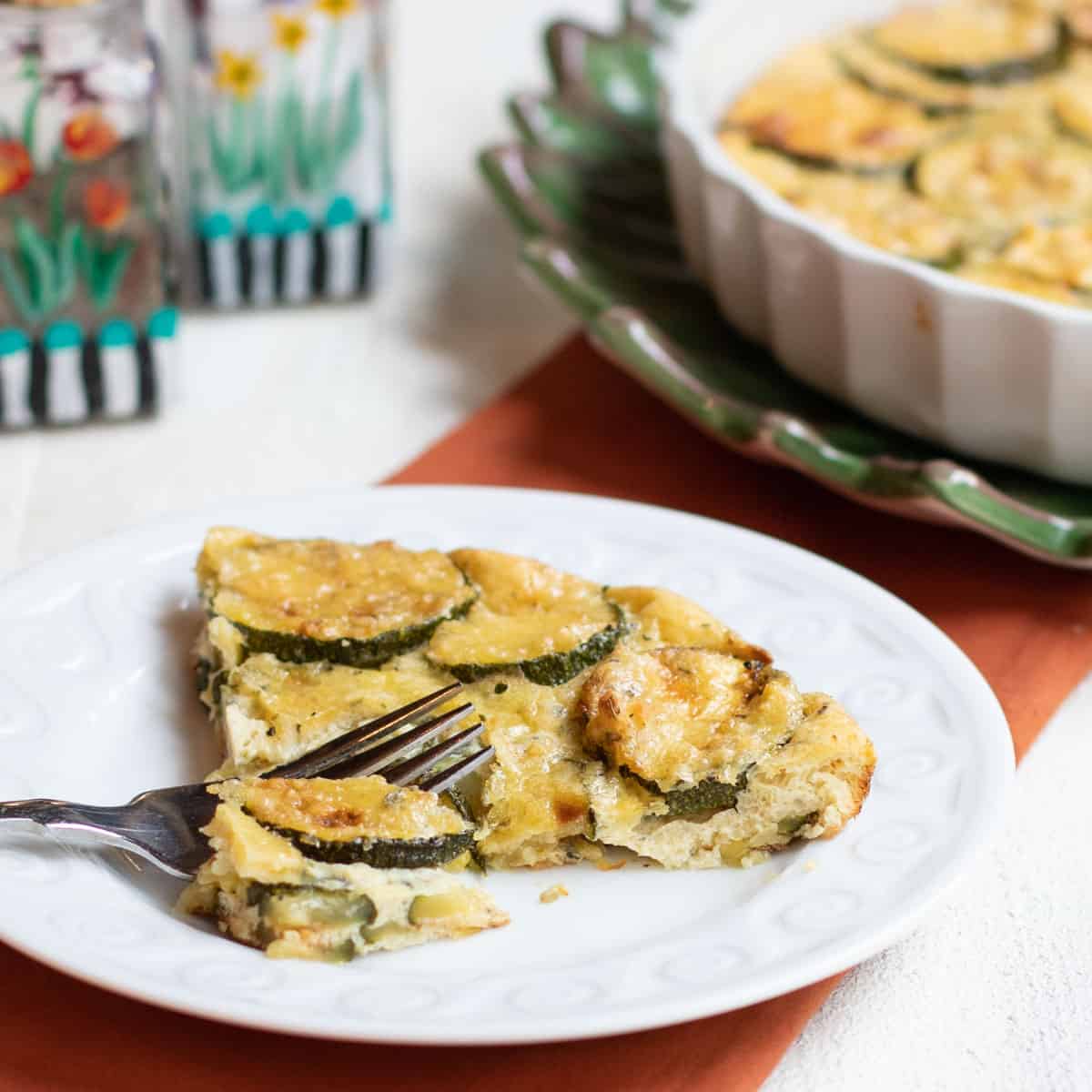 Slice of zucchini custard in front of baking dish