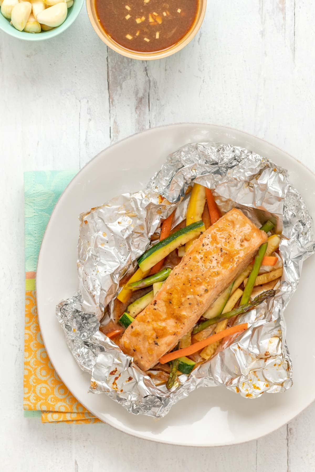 overhead view of salmon and vegetables baked in foil, with foil cut open to show inside